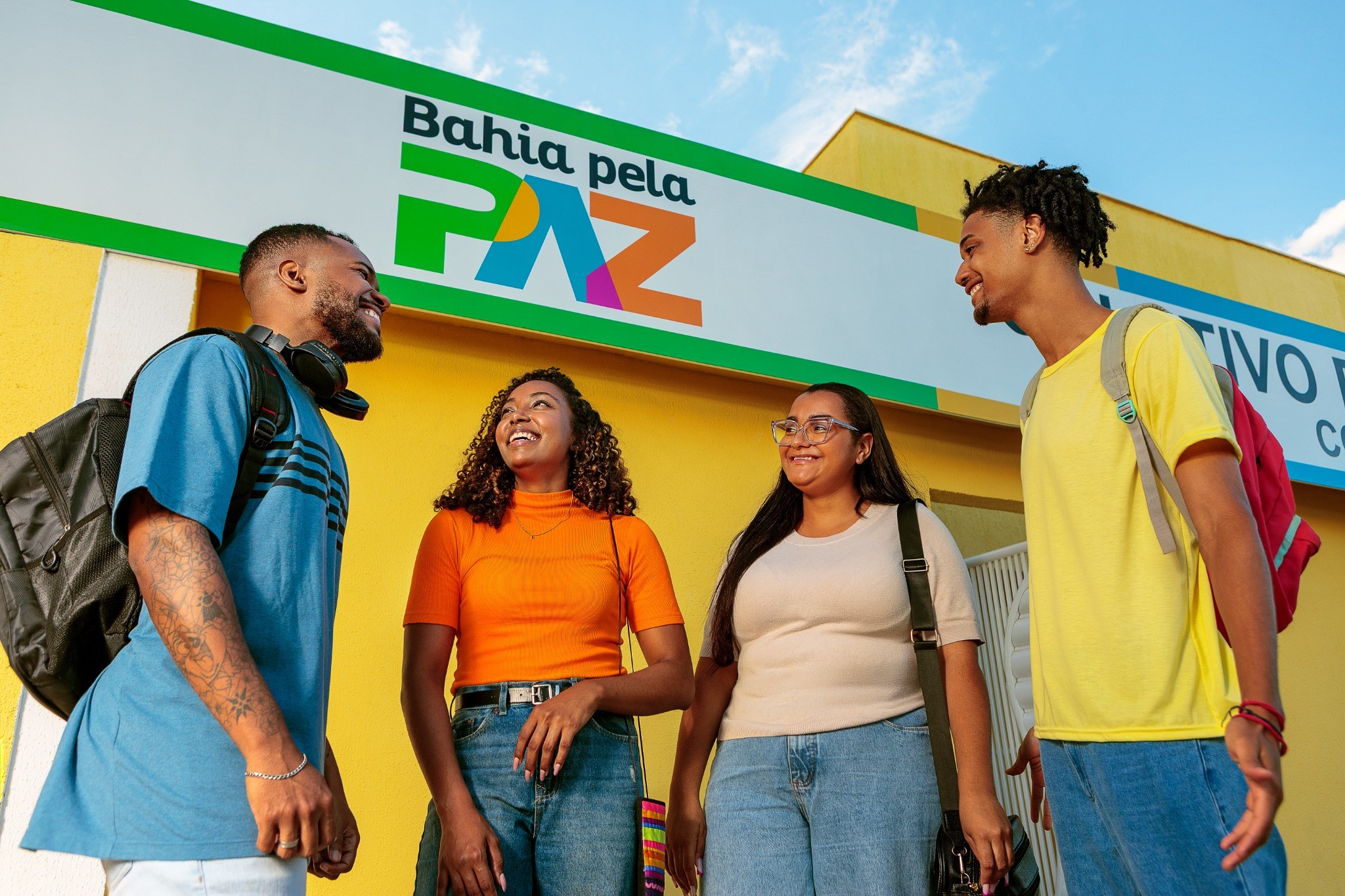 Quatro jovens conversam em frente a um Coletivo Bahia pela Paz