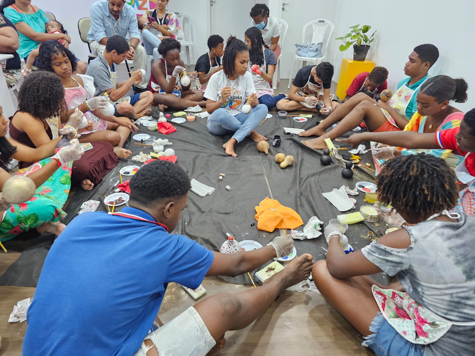 Jovens em roda, pintando cabaças