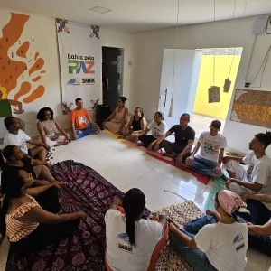 Pessoas sentadas em roda, posição de meditação.