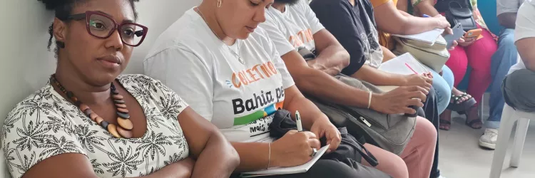 Alunos sentados, com camiseta dos Coletivos Bahia pela Paz, anotando e prestando atenção à aula.