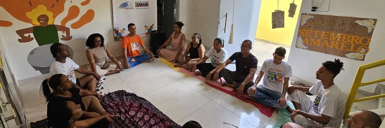 Pessoas sentadas em roda, posição de meditação.