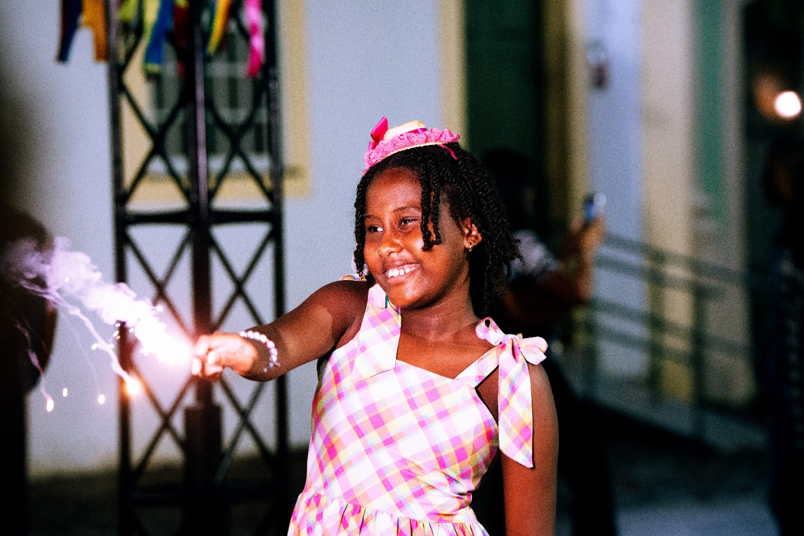 menina negra sorrindo e soltando fogos na festa
