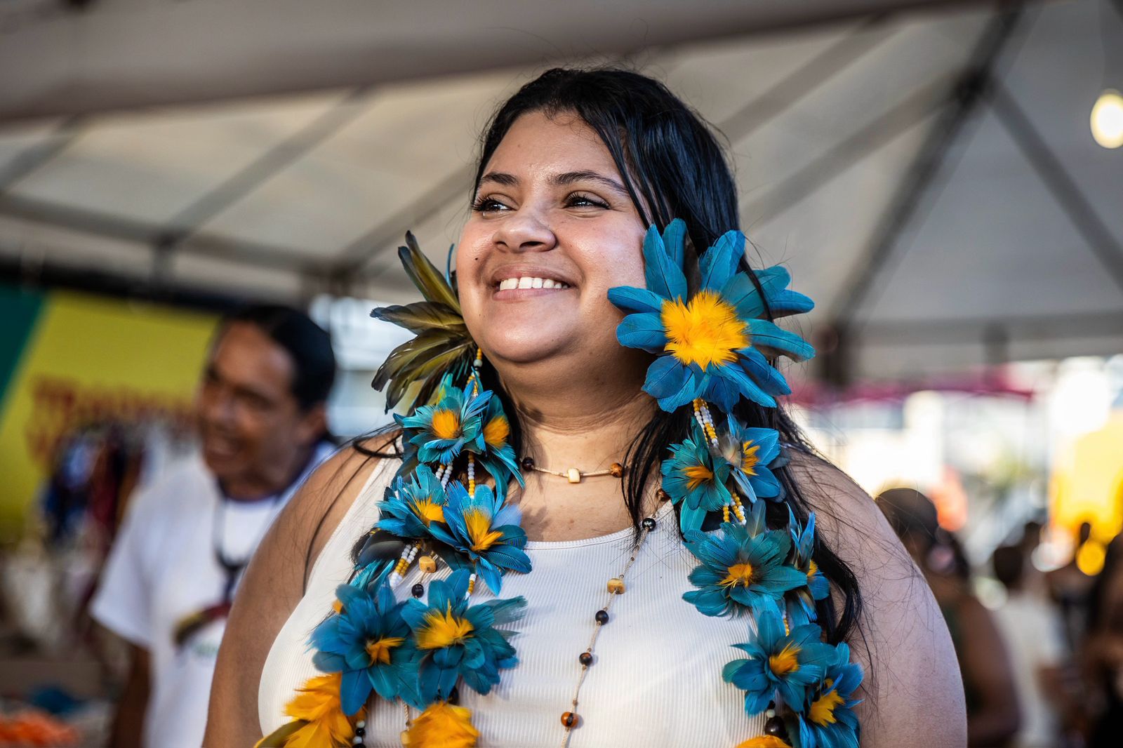 Mulher de comunidade tradicional com colar de flores e sorrido 
