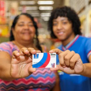 imagem desfocada de mãe e filho com cartão do Bolsa Presença 