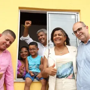 imagem do governador, família beneficiada e demais autoridades locais na janela de uma casa