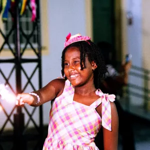 menina negra sorrindo e soltando fogos na festa