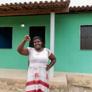 beneficária segurando a chave em frente a Casa