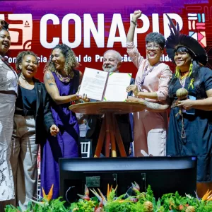 Presidente Lula, ministras e secretária da SEPROMI durante anúncio na conferência 