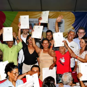 governador e secretário Afonso com beneficiários de programa mostrando títulos de terra