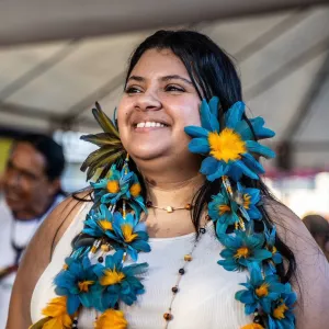 Mulher de comunidade tradicional com colar de flores e sorrido 