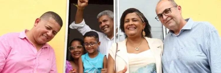 imagem do governador, família beneficiada e demais autoridades locais na janela de uma casa