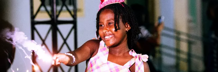 menina negra sorrindo e soltando fogos na festa
