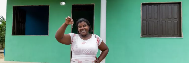 beneficária segurando a chave em frente a Casa