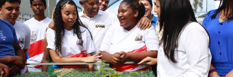 Governador com estudante e professores em horta escolar