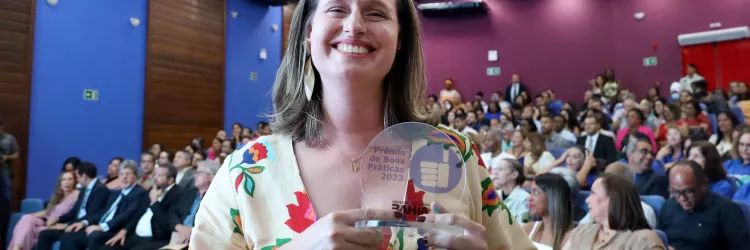 Foto de servidora com placa da premiação 