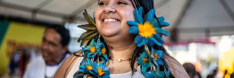Mulher de comunidade tradicional com colar de flores e sorrido 