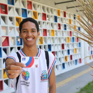 estudante segura e mostra o cartão bolsa presença 