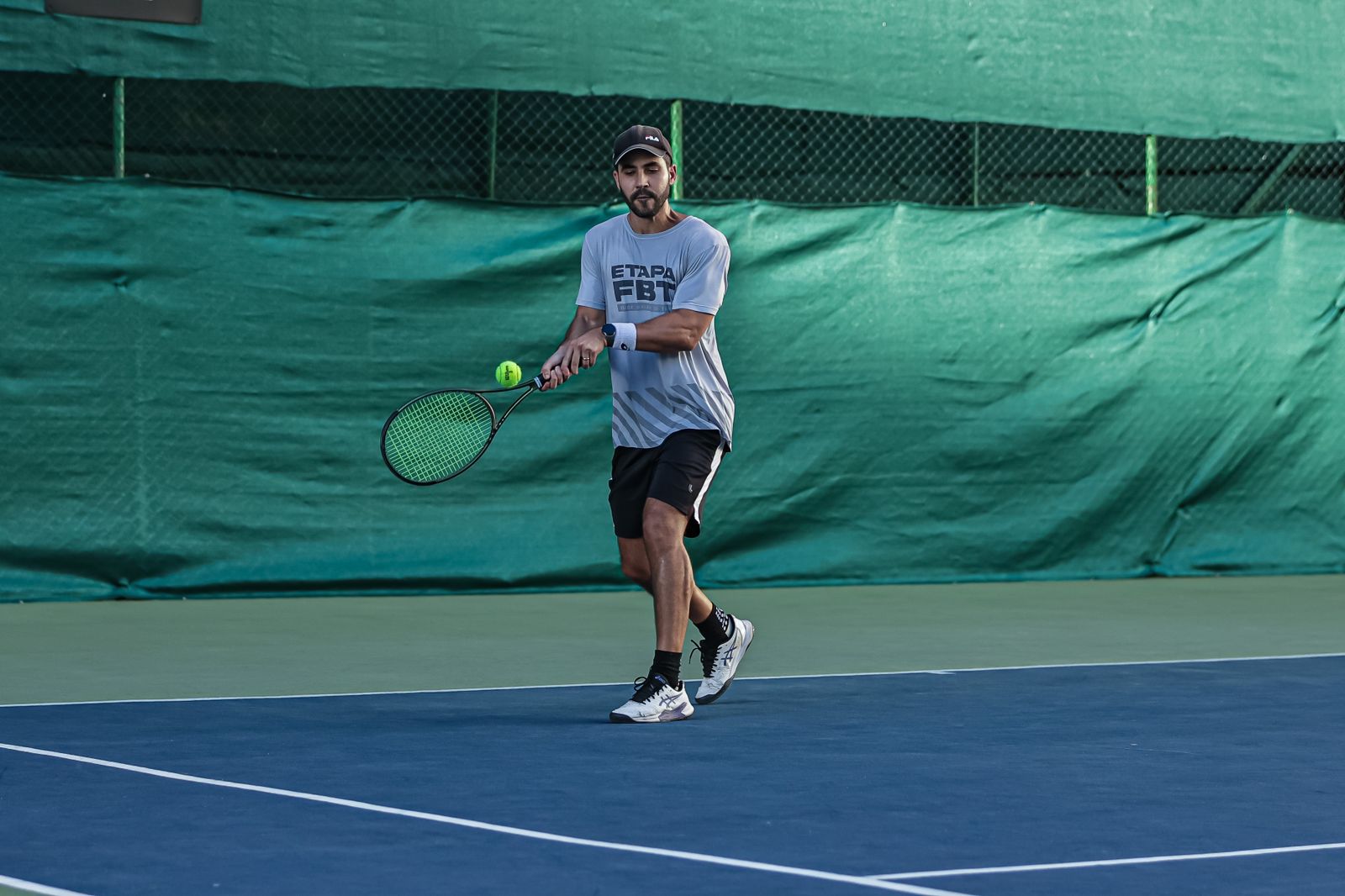 rapaz com a raquete de tênis indo em direção para bater na bola 