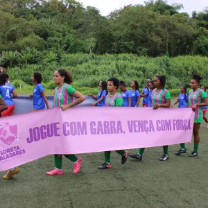 meninas em fila segurando a faixa escrito jogue com garra e vença com força 
