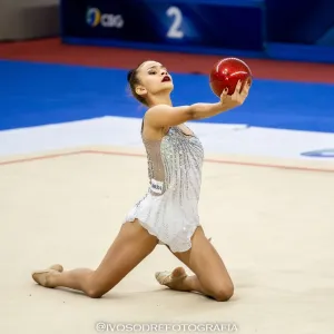 menina no chão de joelhos segurando uma bola vermelha 