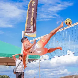 homem chutando a bola por cima da rede de futevôlei