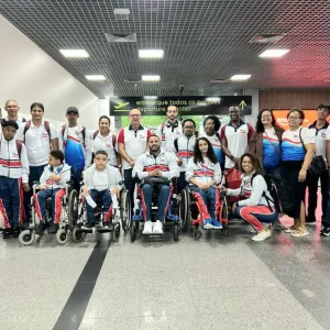 pessoas em pé e mais quatro pessoas na frente sentadas em cadeiras de rodas