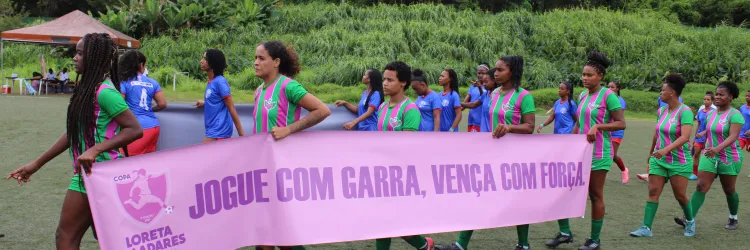 meninas em fila segurando a faixa escrito jogue com garra e vença com força 