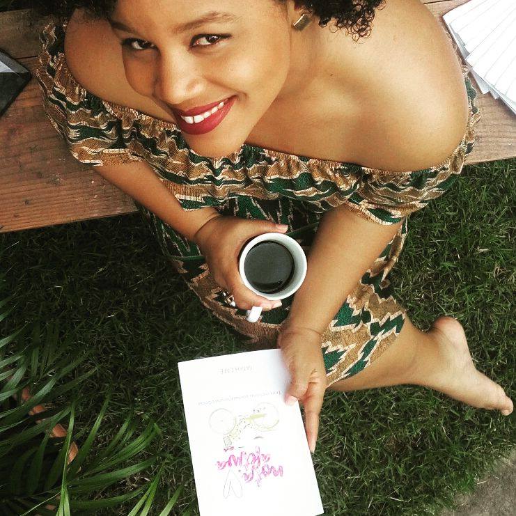 Tatah Café lendo com uma xícara de café na mão