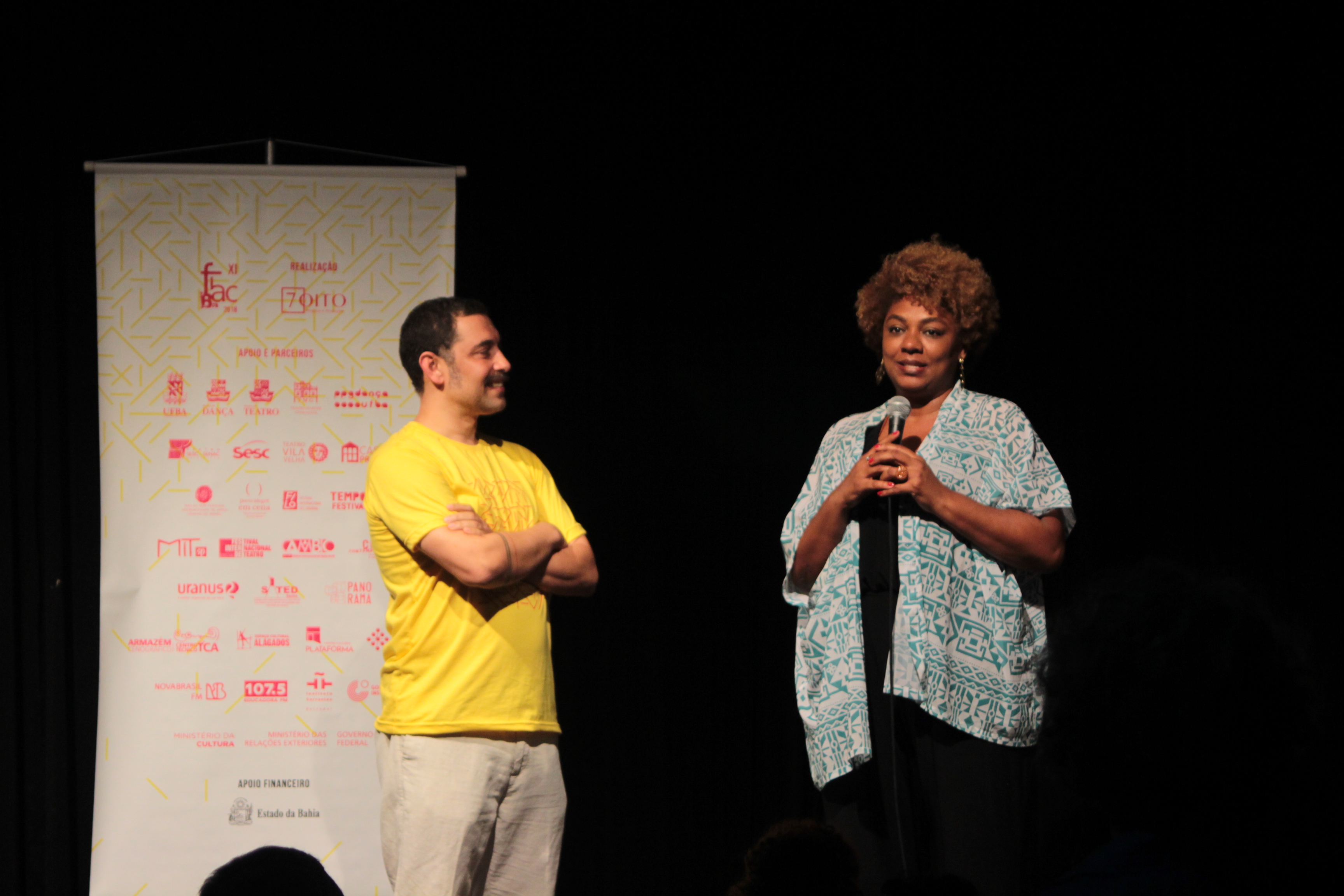 Renata Dias e Felipe Assis no Cabaré dos Novos. Ao lado, plotagem com arte do fiac e patrocinadores