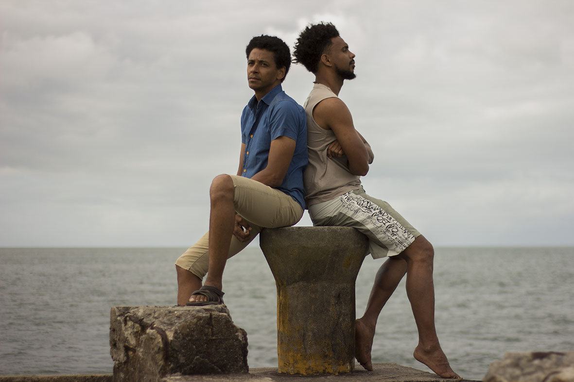 dois homens sentados num banco à beira do mar