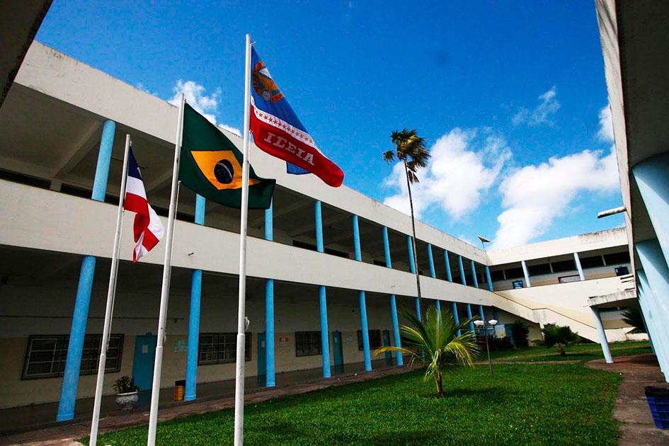 foto da fachada de um prédio. Há 3 bandeiras suspensas à frente dele. 
