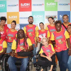 Esta imagem mostra um grupo de pessoas sorrindo, com camisetas coloridas que dizem "RESPEITO É NOSSO DIREITO!". O fundo tem logotipos da SJDH (Secretaria de Justiça e Direitos Humanos) e PROCON BA, indicando que é um evento na Bahia, Brasil, promovido pelo governo do estado. A presença de pessoas com deficiência sugere que o evento pode estar relacionado à inclusão e direitos das pessoas com deficiência.