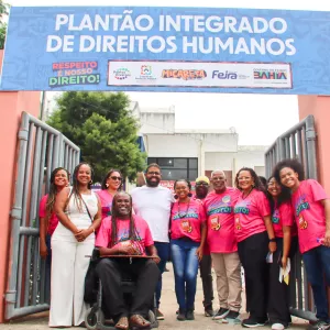 Abertura do Plantão Integrado. varias pessoas na frente do protão do Colégio, local sede do Plantão. No protão, há uma placa enorme com o nome do plantão, com o fundo azul.