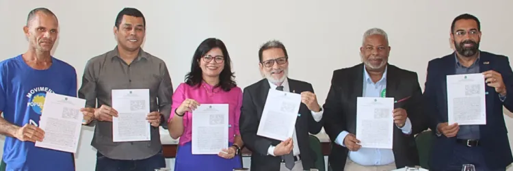 UFBA e SJDH assinam termo de cooperação. Representantes mostram o documento que simboliza o acordo. 