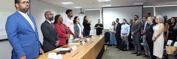 Secretário felipe no II Encontro Sinase. ele veste terno azul e está em pé, é um homem negro que usa óculos. 