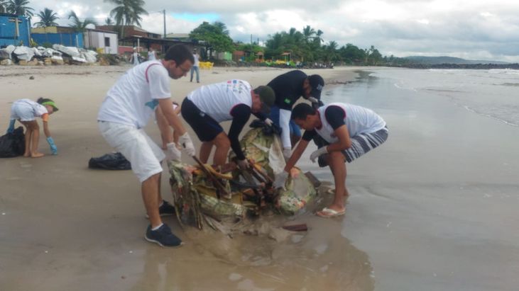 Foto: Voluntários retiram um sofá enterrado na areia da praia