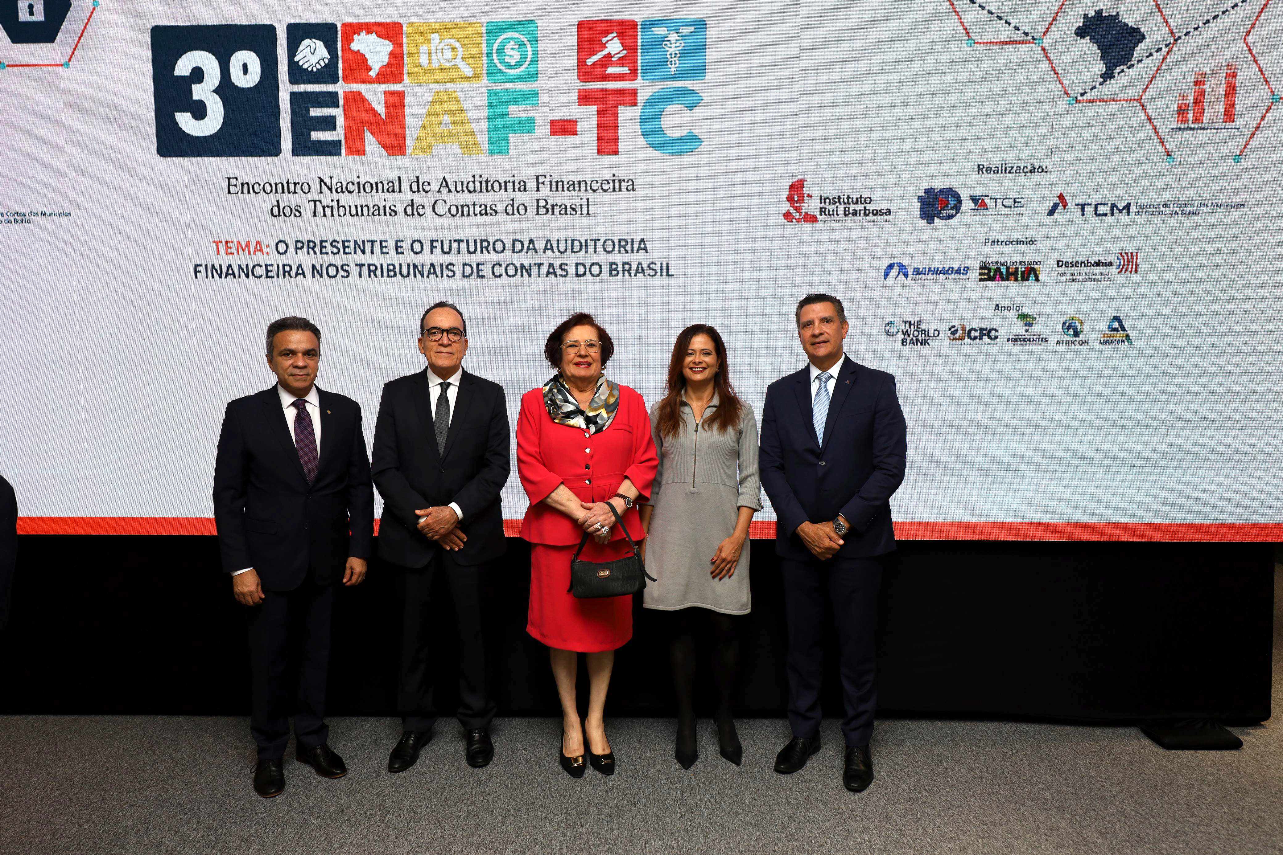 Grupo de cinco pessoas em trajes formais posando em frente ao painel do 3º Encontro Nacional de Auditoria Financeira dos Tribunais de Contas do Brasil (ENAF-TC).