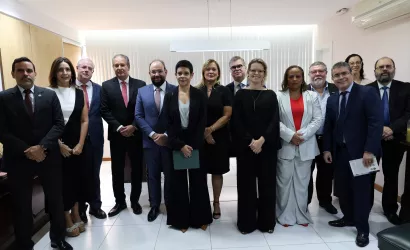 Um grupo de quatorze pessoas posa para foto oficial em uma sala bem iluminada. A maioria veste trajes formais e ternos de cores variadas, como preto, azul, cinza e branco.