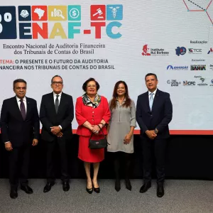 Grupo de cinco pessoas em trajes formais posando em frente ao painel do 3º Encontro Nacional de Auditoria Financeira dos Tribunais de Contas do Brasil (ENAF-TC).