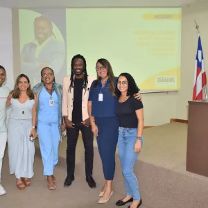 Foto em grupo com o palestrante e participantes ao final do workshop. Todos posam sorrindo em frente à tela de projeção que identifica o evento. A imagem registra o encerramento da atividade e o clima de integração entre os envolvidos.