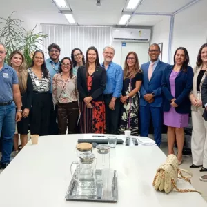 Foto posada do grupo após a reunião. Cerca de quinze pessoas ficam lado a lado sorrindo para a câmera. A mesa à frente tem copos e garrafas. Todos vestem roupas formais ou sociais em uma sala bem iluminada.