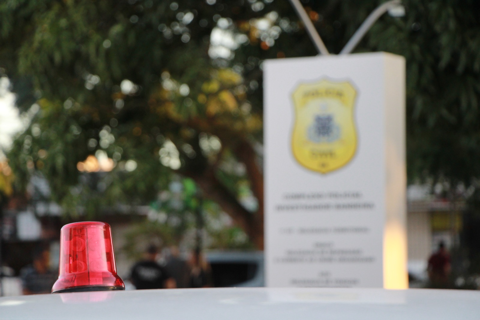 Giroflex com placa da delegacia ao fundo