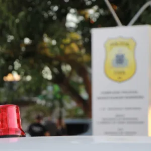 Giroflex com placa da delegacia ao fundo