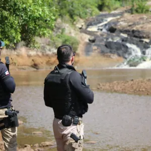 Policiais em campo nas margens de uma cachoeira