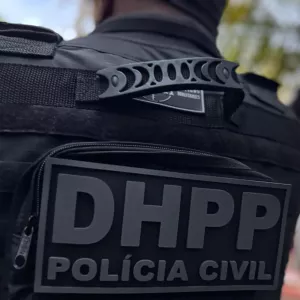 Detalhe das costas de um agente da Polícia Civil com colete tático identificado com o emblema “DHPP POLÍCIA CIVIL”