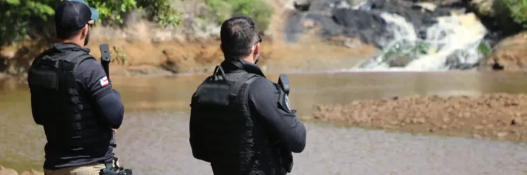 Policiais em campo nas margens de uma cachoeira
