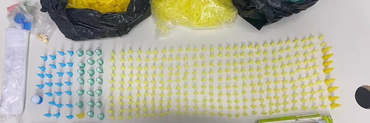 Materiais de tráfico apreendidos pela Polícia Civil, como cápsulas, balança e celulares, dispostos sobre uma mesa.