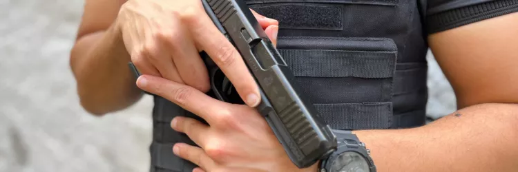 Agente da Polícia Civil vestindo colete tático com identificação “INVESTIGADOR”, segurando uma pistola com as duas mãos em posição de prontidão.