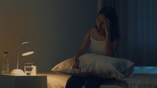 Beautiful Asian young woman sitting on bed take sleeping pill or