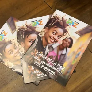 A imagem mostra três livros iguais em uma bancada marrom